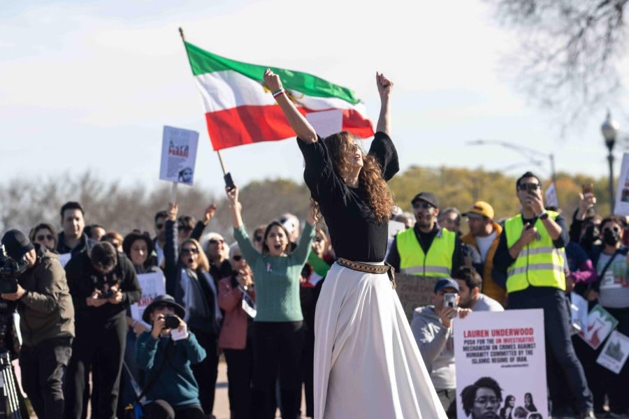 Protesters demonstrate against the Iranian regime, with an Iranian flag prominently displayed.
