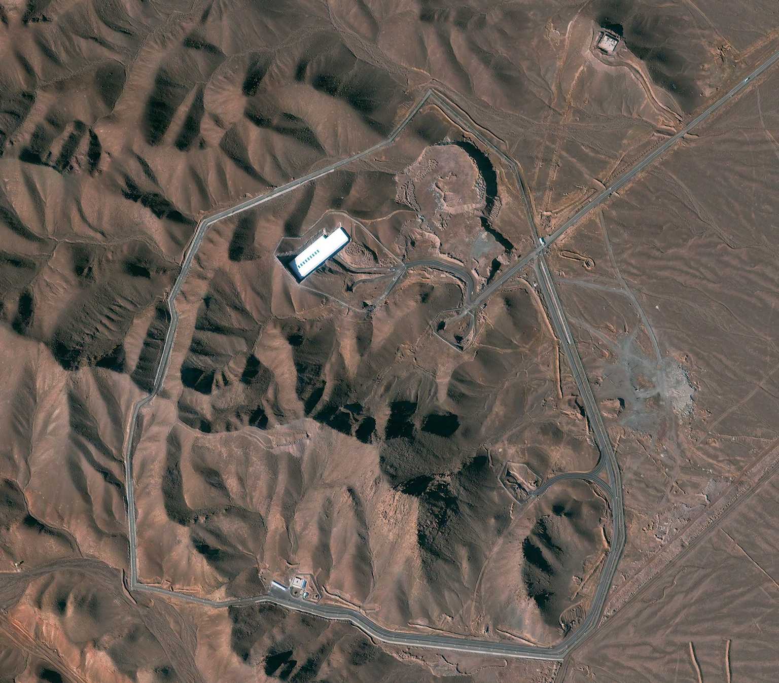 Aerial view of Iran's Fordow Fuel Enrichment Plant, nestled within a mountainous desert landscape.