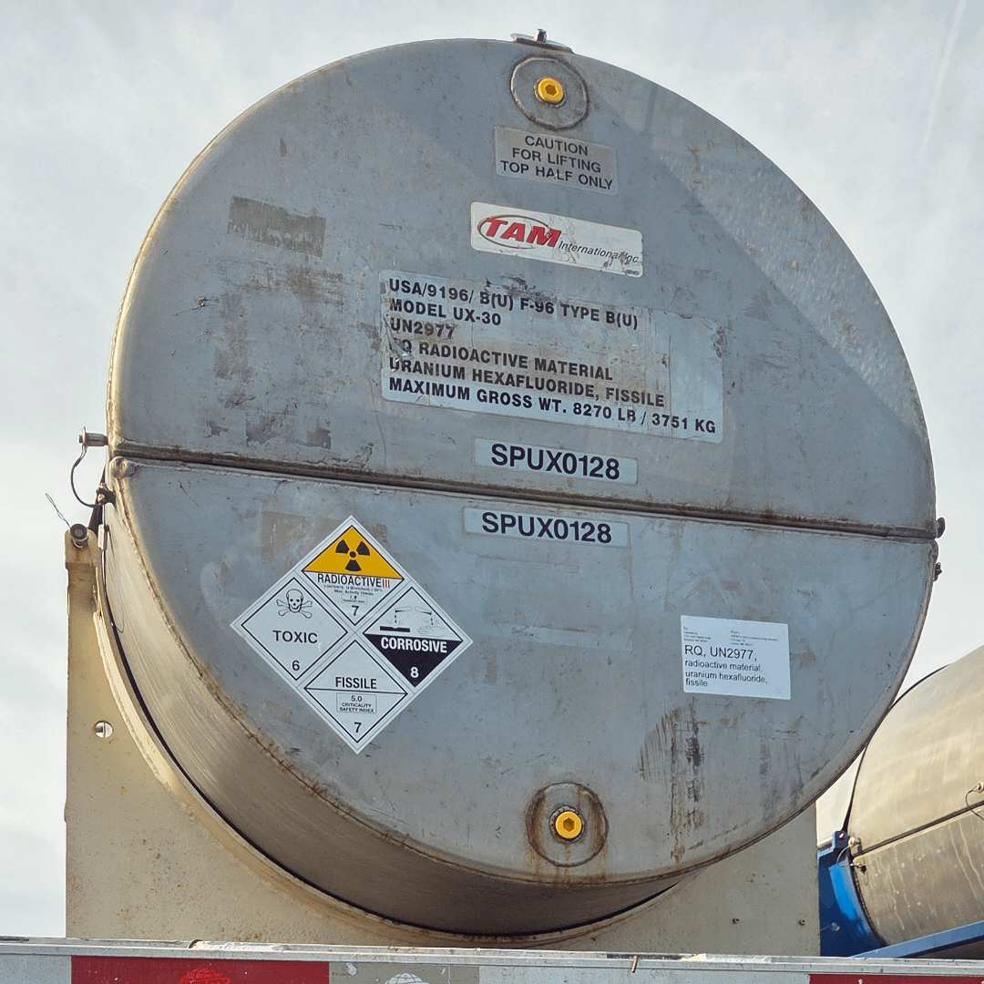 A robust cylindrical container labeled for the transport of Uranium Hexafluoride (UF6), the material used in gas centrifuges for uranium enrichment.