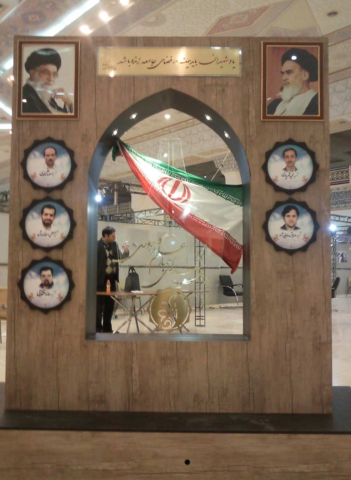 A memorial honoring Iranian nuclear scientists who were assassinated, featuring their portraits and an Iranian flag.