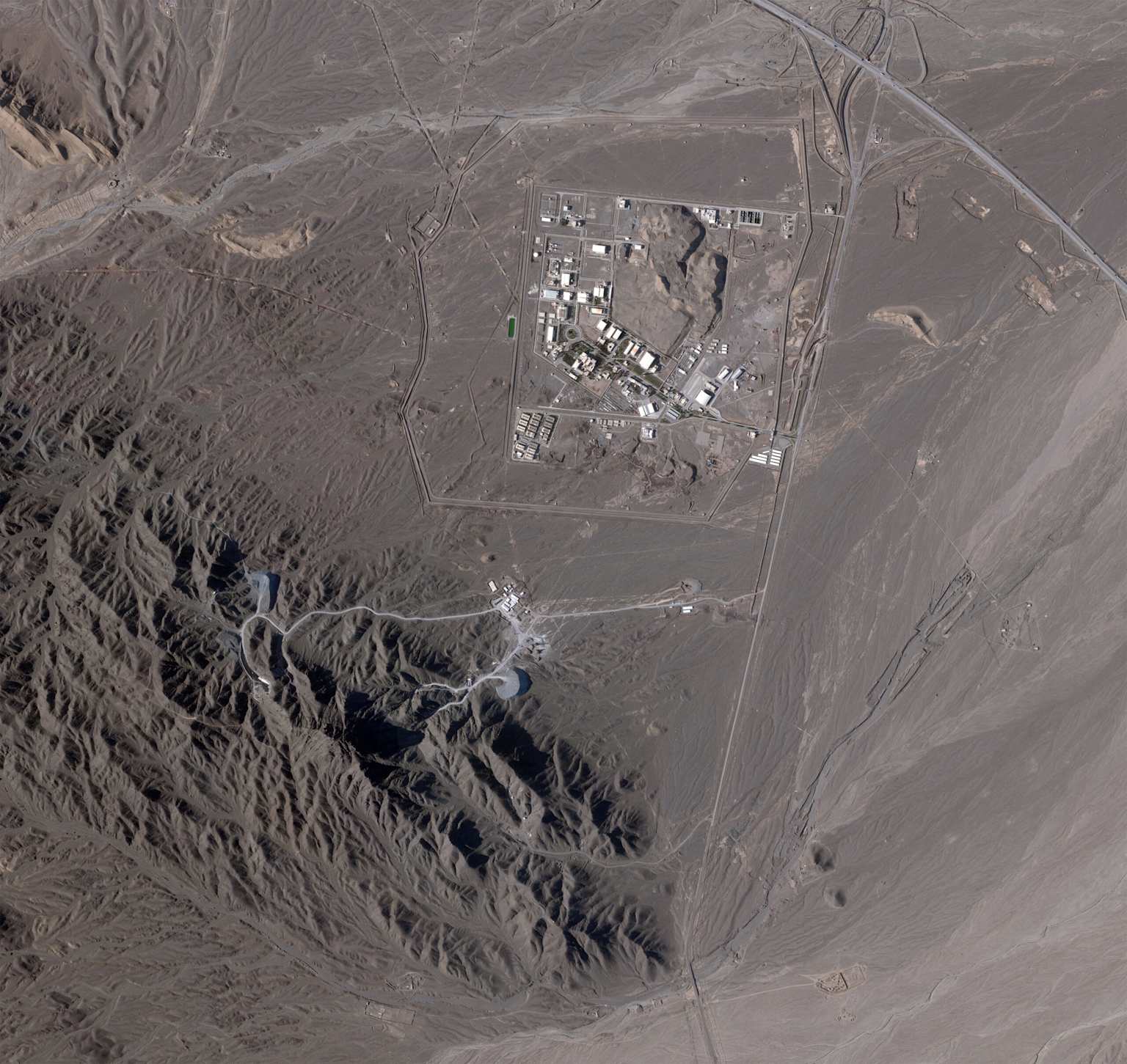 Overhead view of the Fordow Fuel Enrichment Plant in Iran, an underground uranium enrichment facility nestled within mountainous terrain.