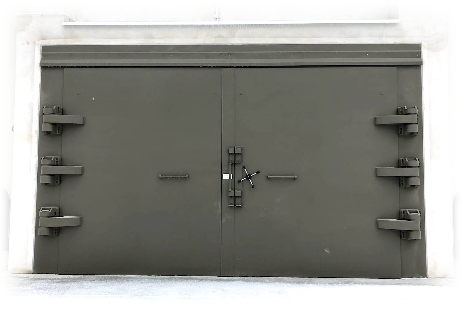 A heavy-duty, military-grade double blast door with a robust locking mechanism and multiple hinges, designed for a hardened underground bunker.