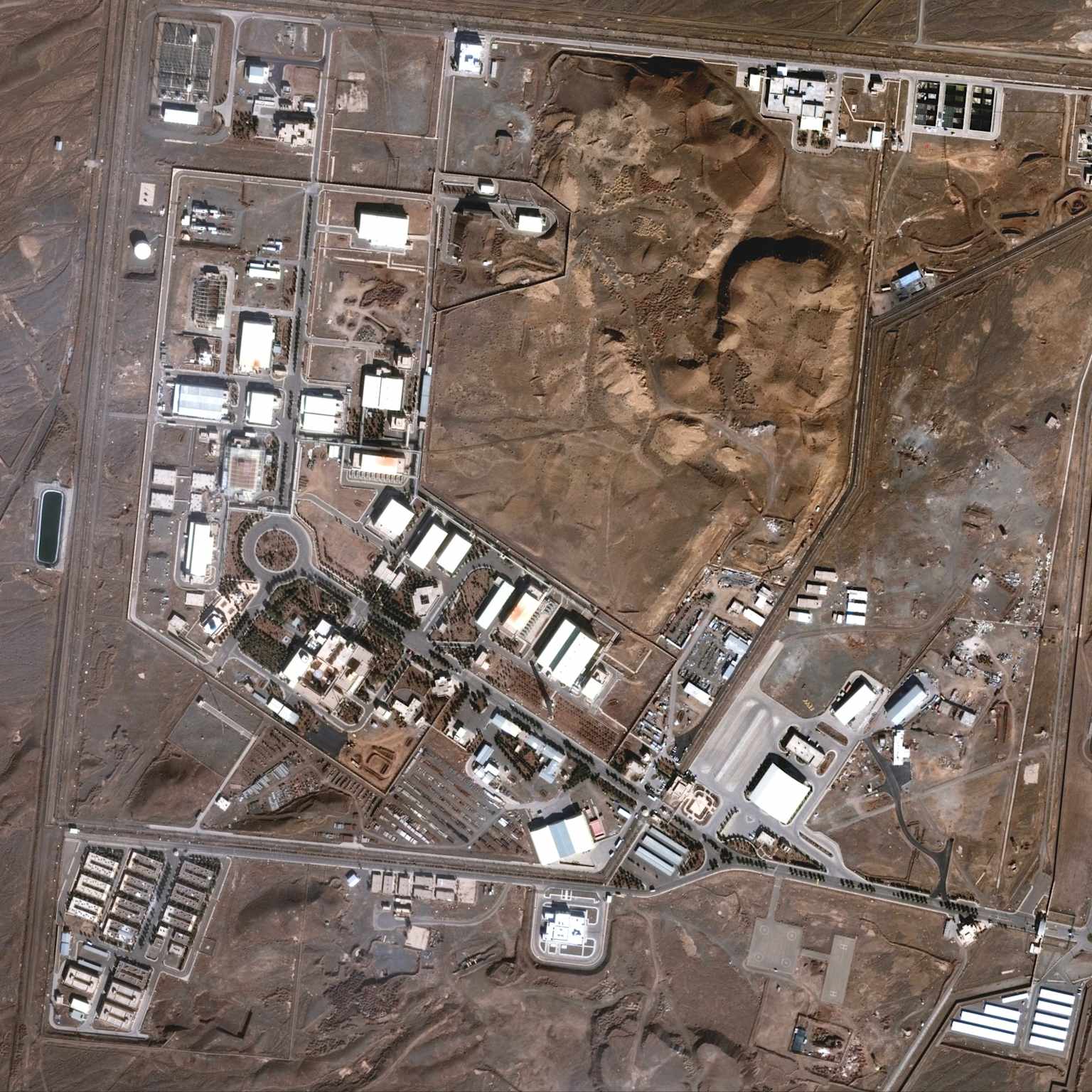 Aerial view of the Natanz nuclear facility in Iran, showing its extensive complex of buildings and surrounding arid landscape.
