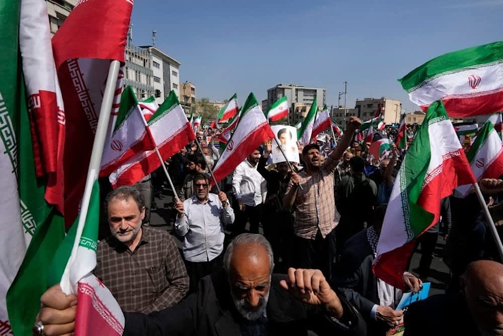 Iranian citizens hold national flags during a public rally.