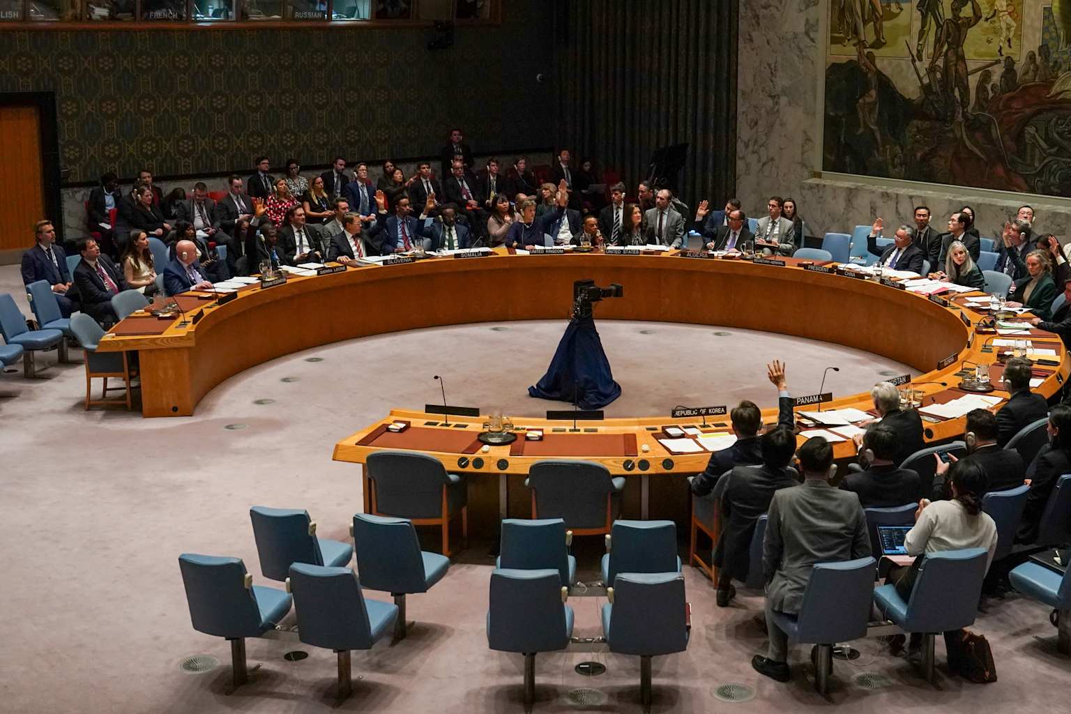 UN Security Council meeting with delegates voting around a circular table